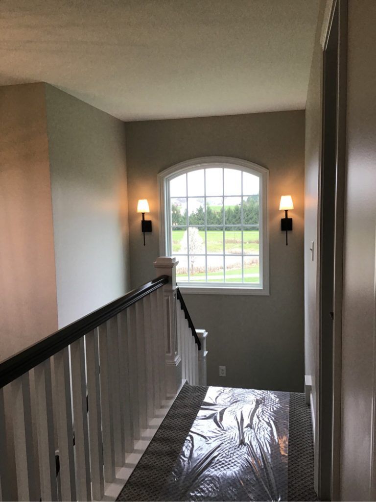 A staircase with a window, railing and two lights inside of a house.