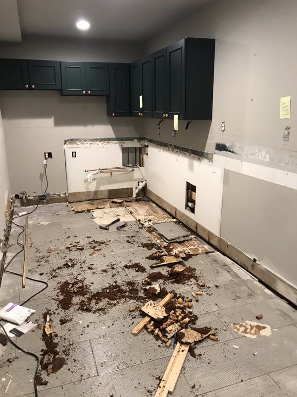 A kitchen under construction with a lot of trash on the floor.