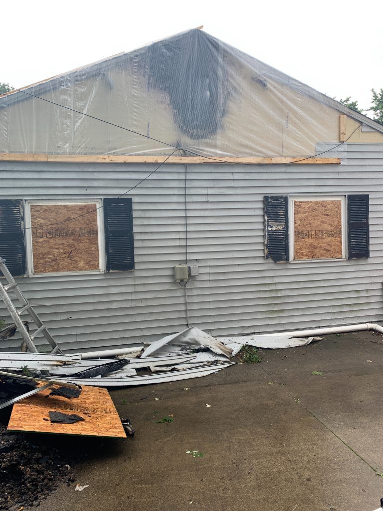 A house that has been damaged by a fire and is covered in plastic.