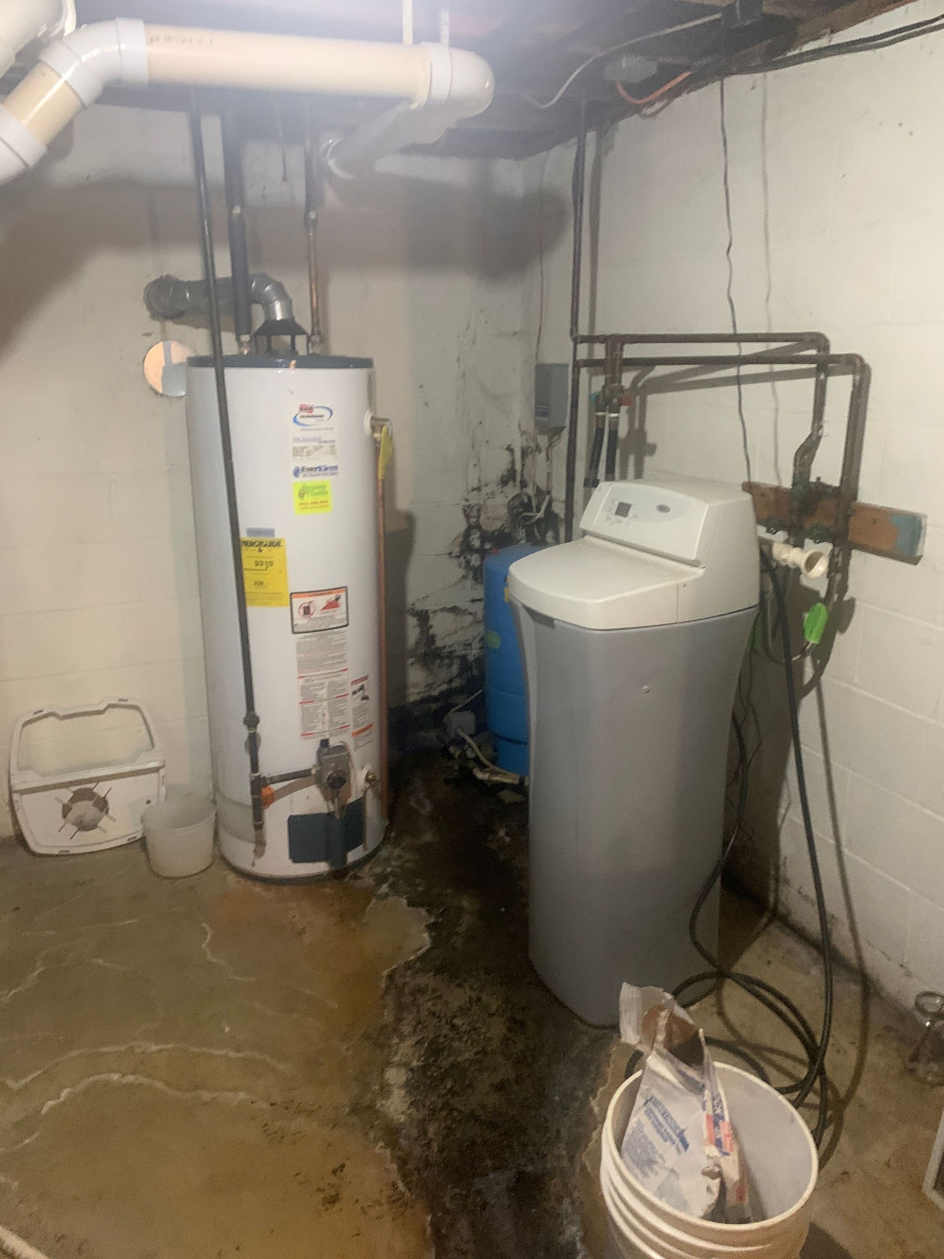 A water heater and a water softener are in a basement.