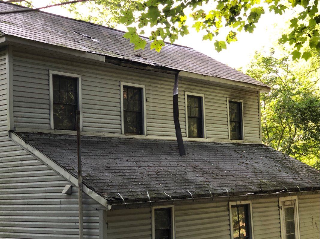 A house with a roof damaged by falling tree. 