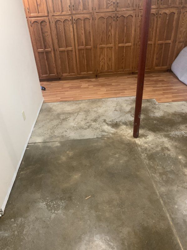 A concrete floor in a basement with wooden cabinets.