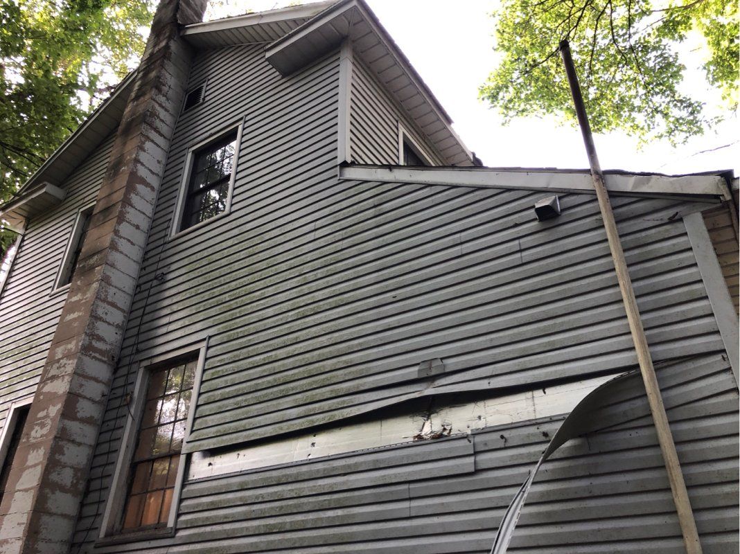 The side of a house damaged by falling tree. 