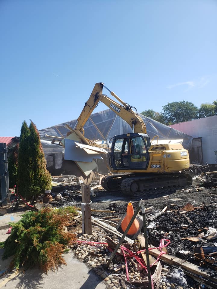 A large yellow excavator is being used to demolish a building.