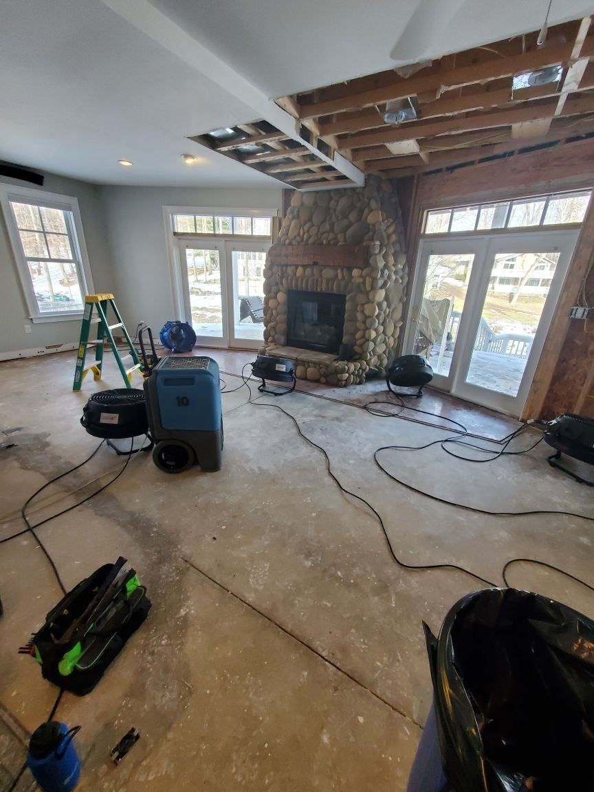 A living room with a fireplace an industrial machine on the floor.