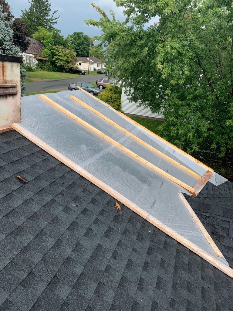 The roof of a house is being repaired and covered in plastic.