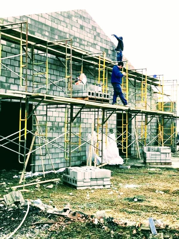 A group of construction workers are working on a brick building.