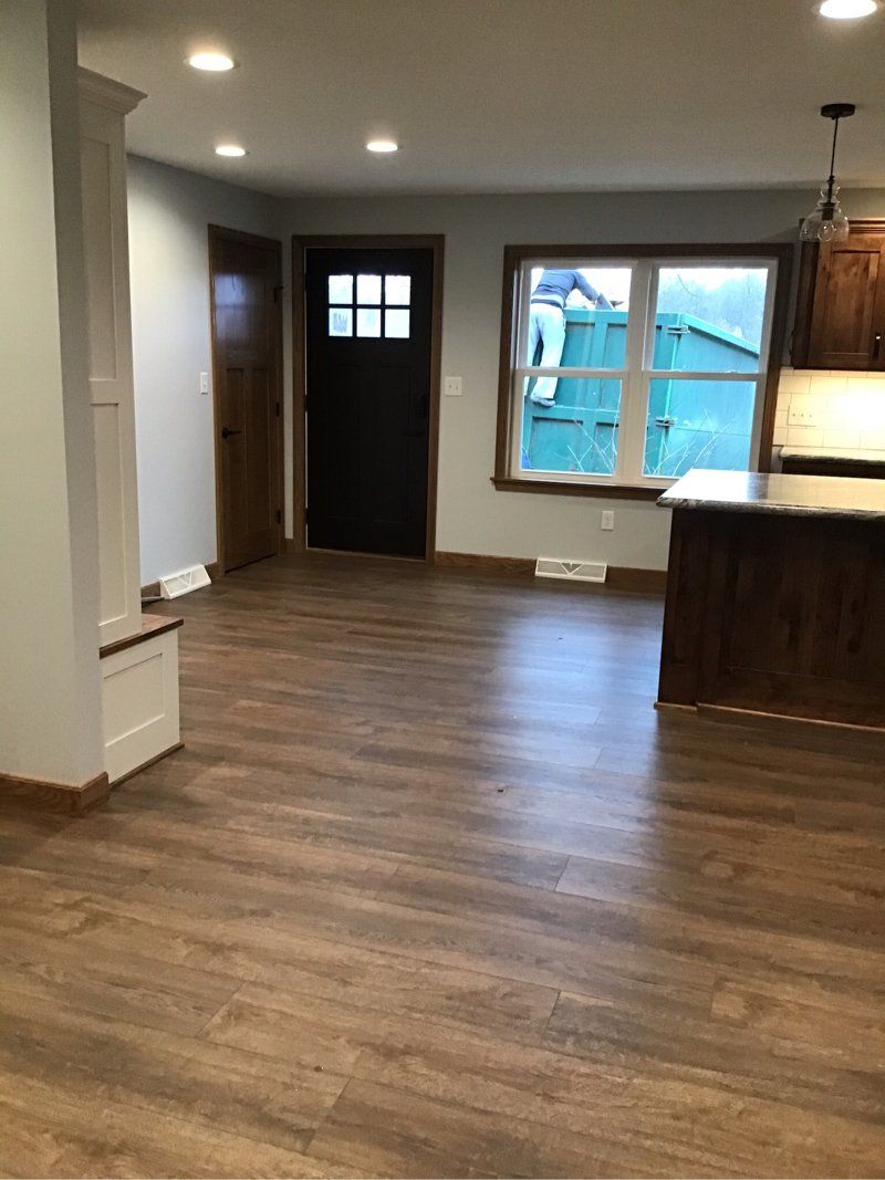 A living room with hardwood floors and a kitchen in the background.