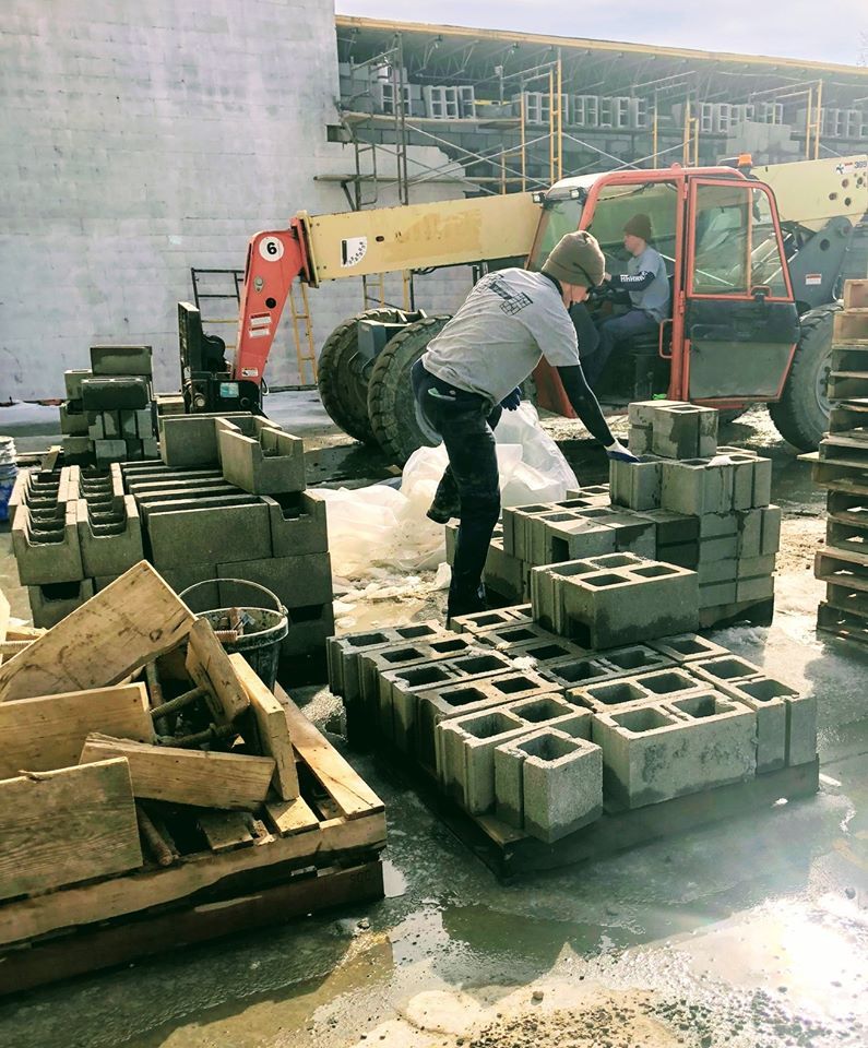 A man is working on a pile of concrete blocks.