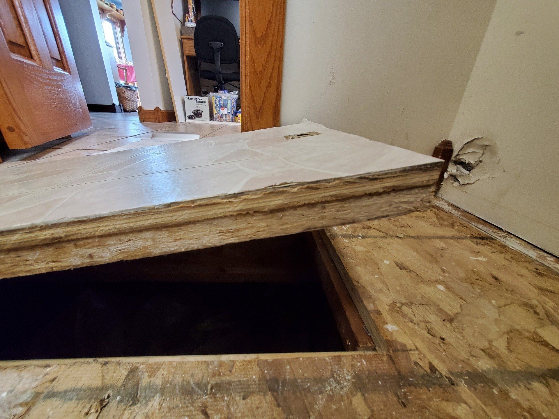 A wooden floor with water damage and a hole in it. 