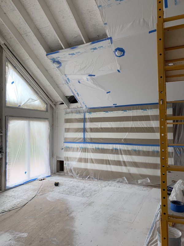 A room that is being repaired and painted with a ladder in the foreground.