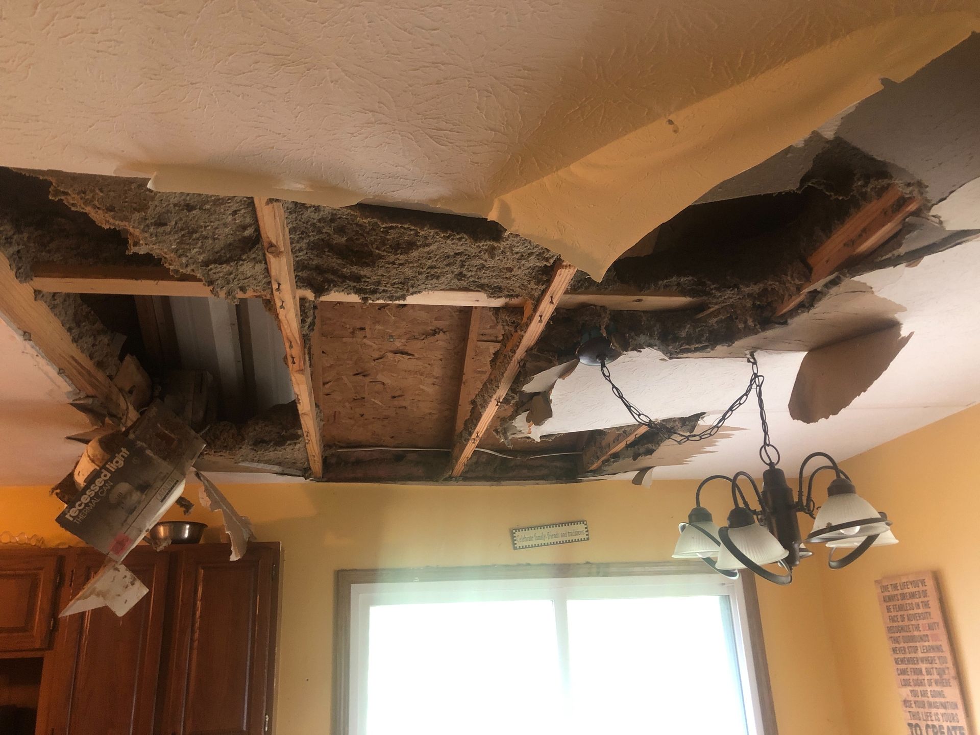 A ceiling with a hole in it and a chandelier hanging from it.