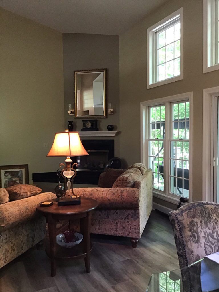 A living room with a table, couch, fireplace, and lamp.