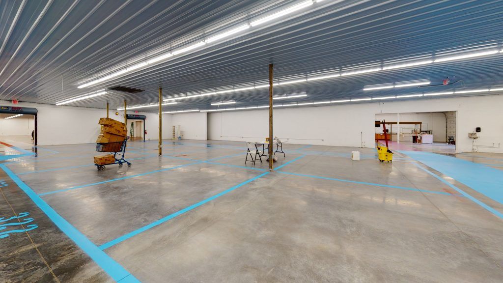 A large empty warehouse with blue lines on and numbers the floor.