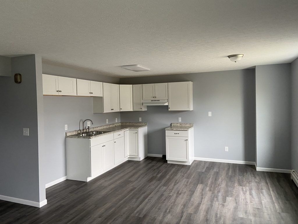 An empty kitchen with white cabinets and gray walls.