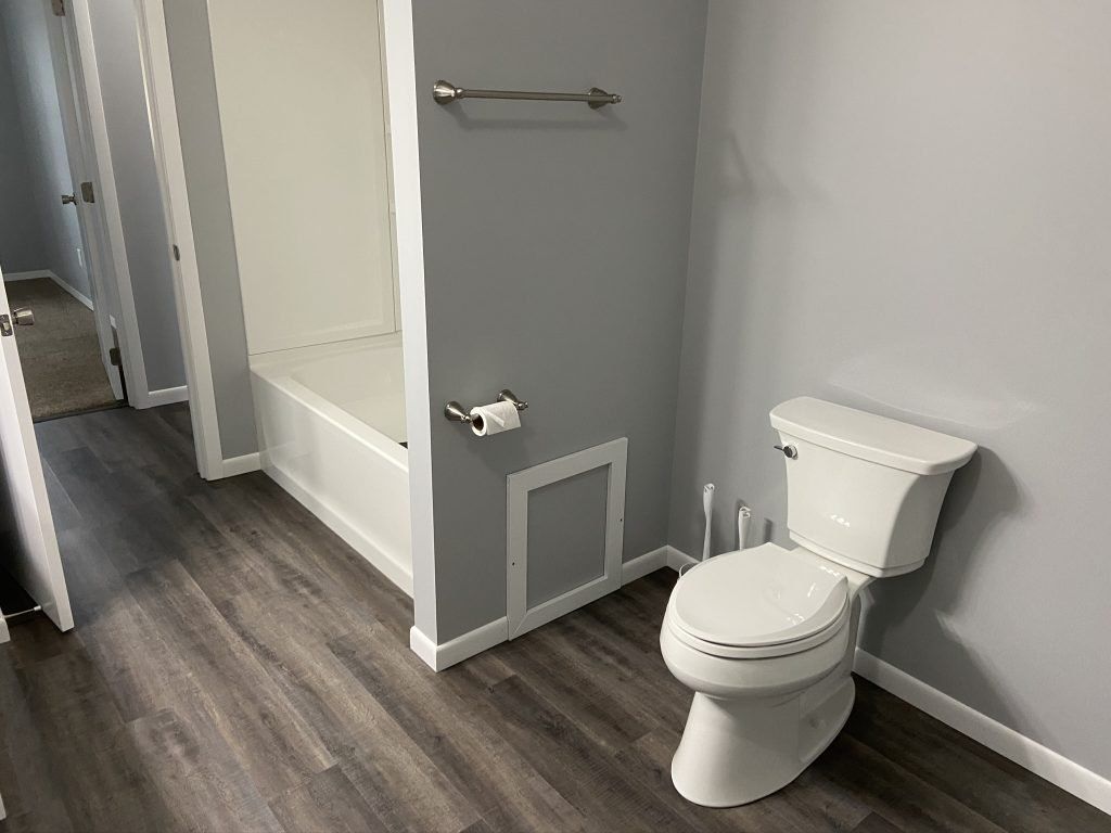 A bathroom with a toilet, toilet paper, a bathtub, and towel rack.
