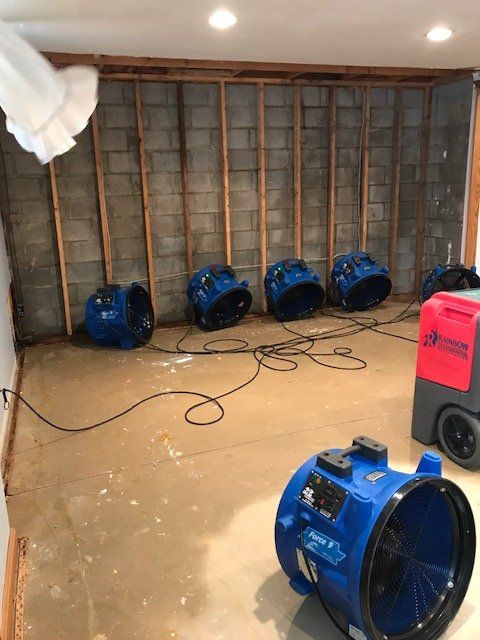A room with industrial fans beside a brick wall.