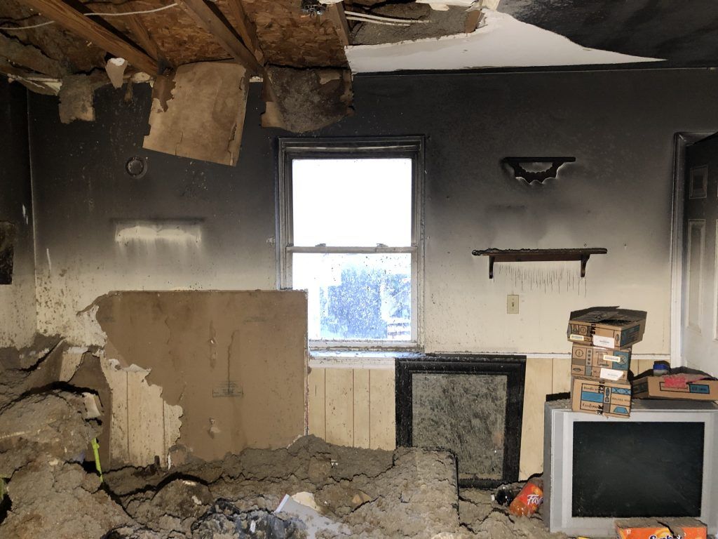 A room with a tv and a window that has been damaged by a fire.