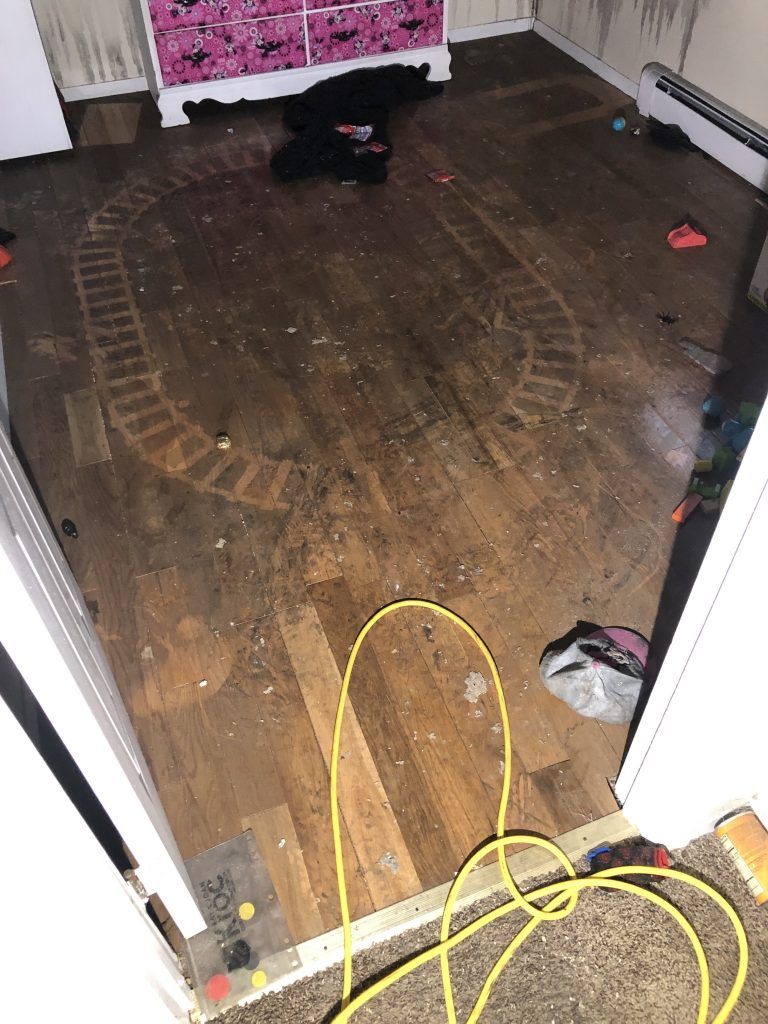 A room with a train track on the floor and a yellow cord.