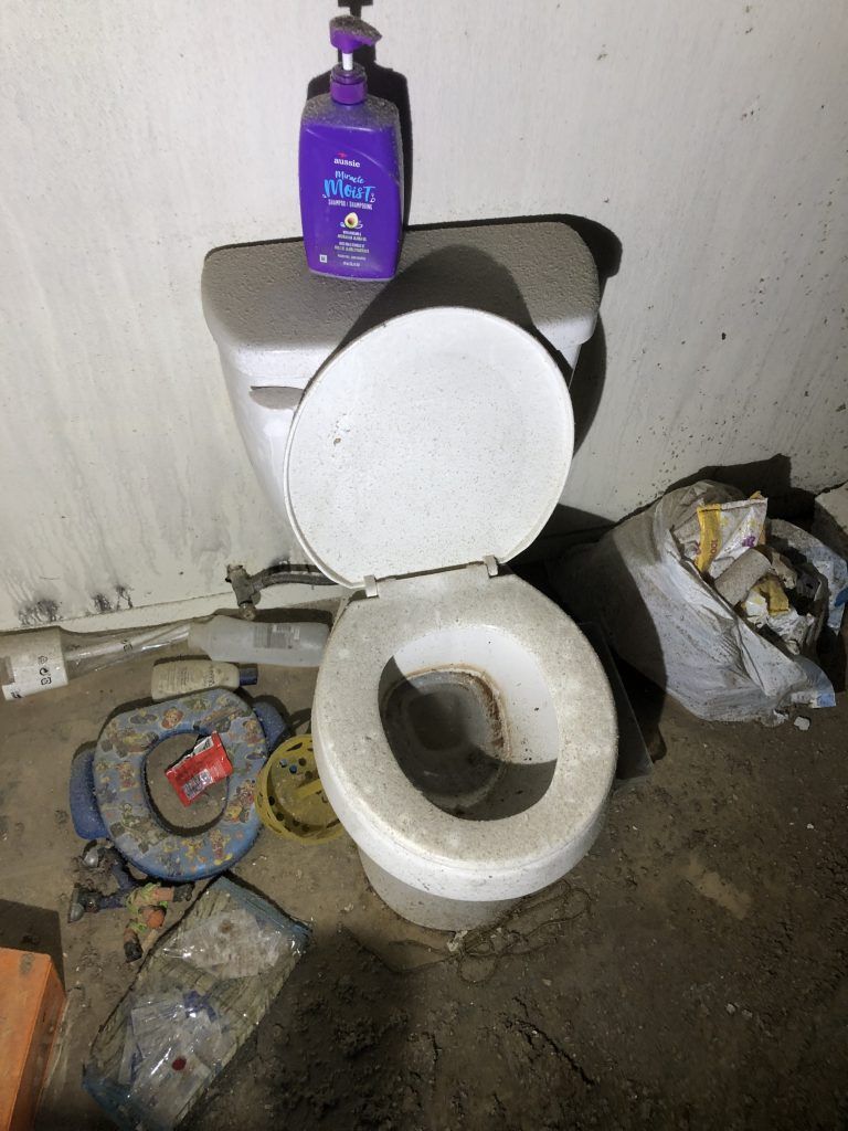 A fire damaged room with a toilet with a bottle of soap on top of it.