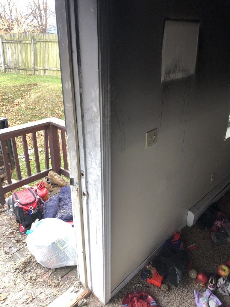 A room with a door open and a lot of trash on the floor.