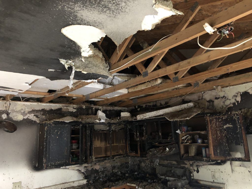 A kitchen with a ceiling that has been damaged by a fire.