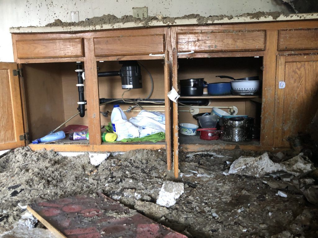 A fire damaged kitchen with pots and pans in the cabinets. 