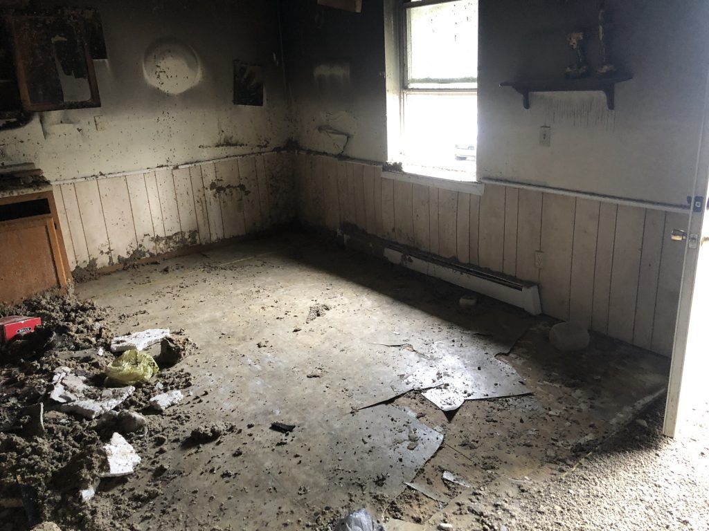 A fire damaged room with dirt on the floor and a window.