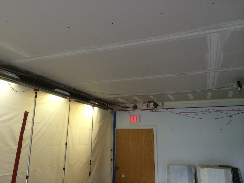 A room with a ceiling and a door with a red exit sign.