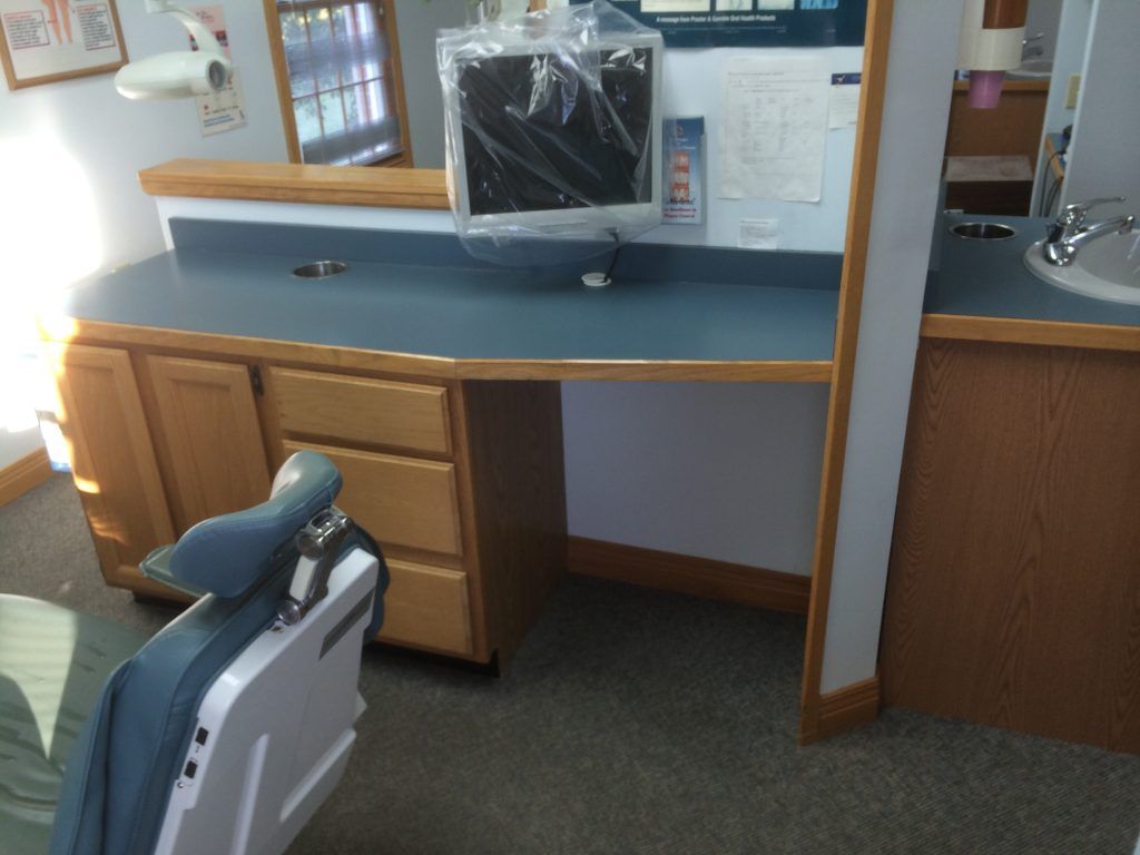 A dental office with a chair and a desk.
