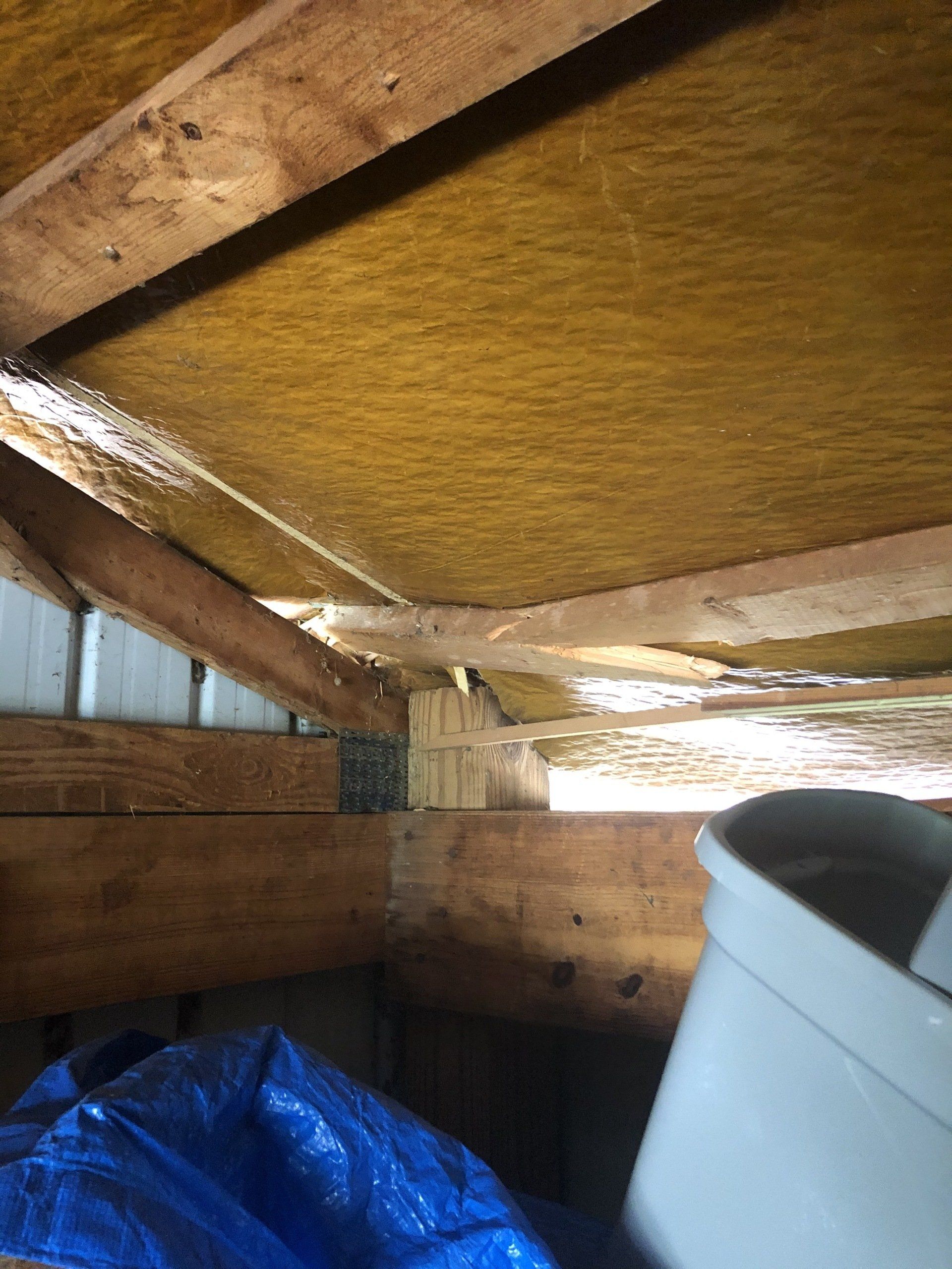 The ceiling of a building with a blue tarp and a trash can inside. .