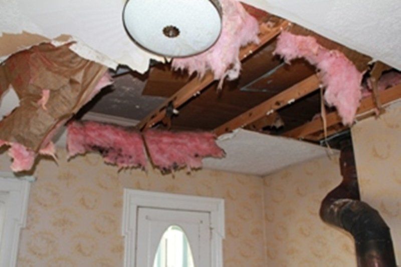 A room with pink insulation hanging from the ceiling has been damaged by a house fire.
