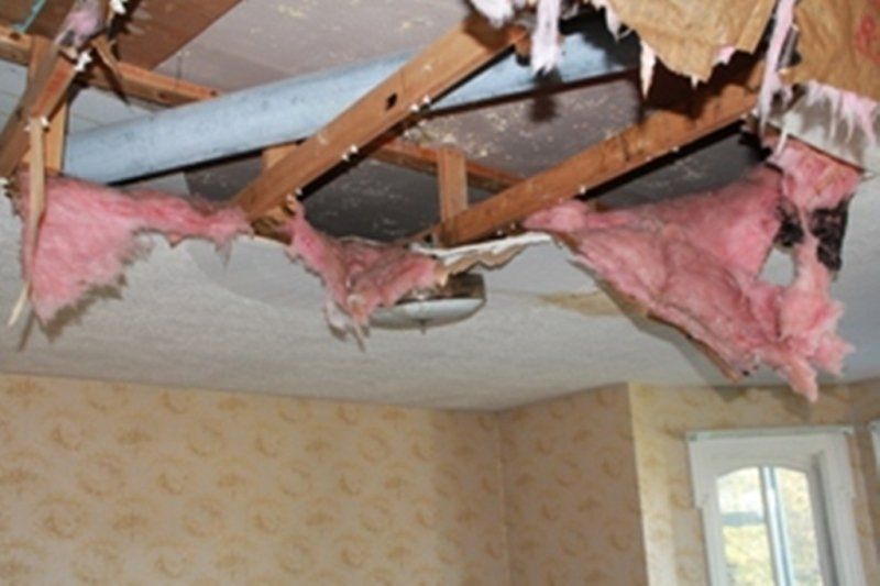 A room with pink insulation hanging from the ceiling has been damaged by a house fire.