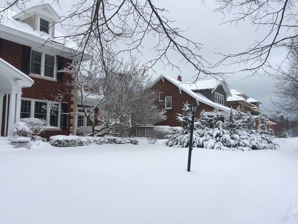 A row of houses are covered in snow in a snowy neighborhood.