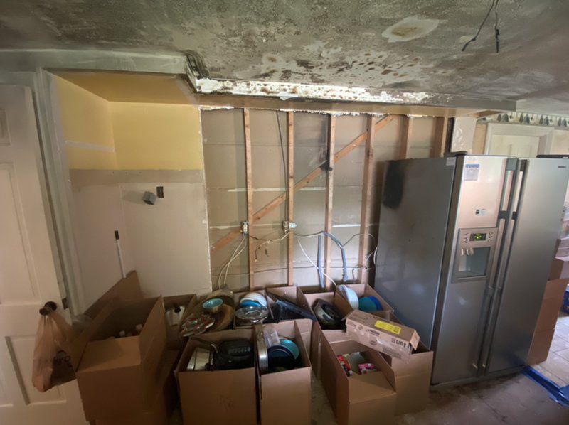 A fire damaged room with boxes and a refrigerator in it.