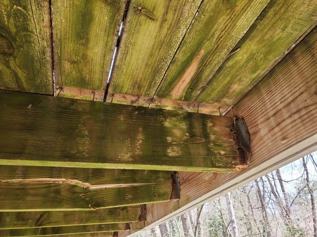 A wooden deck with green moss growing on it.