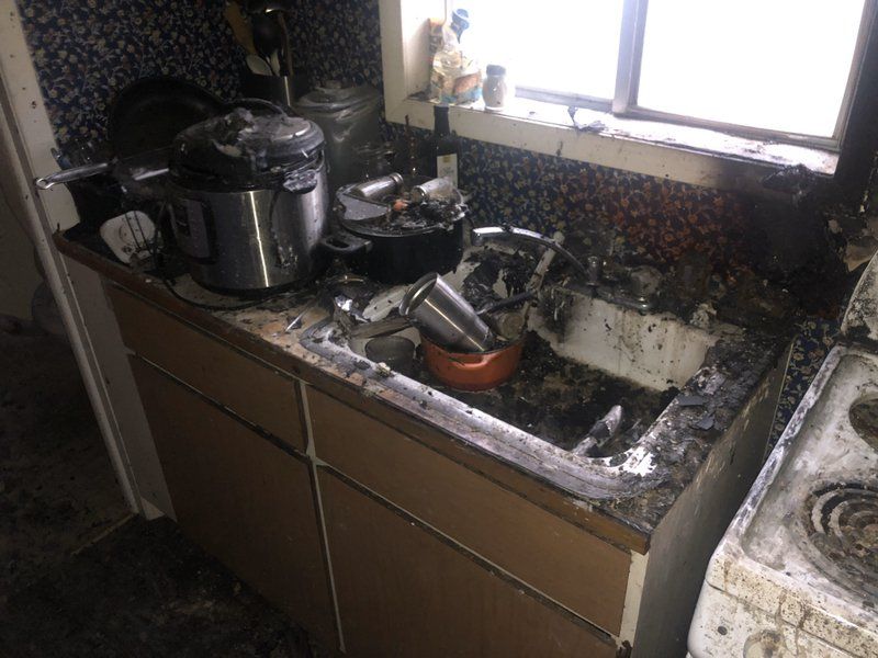 A kitchen with a sink , stove , pots and pans on the counter.