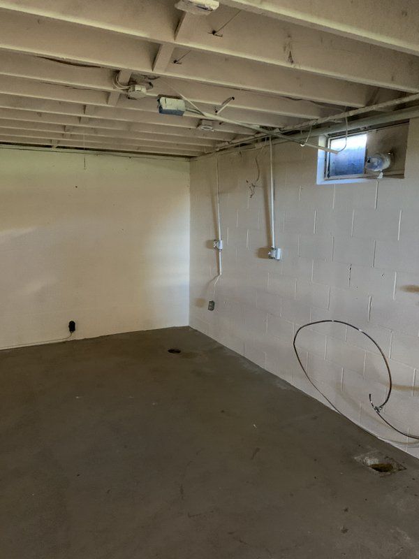 An empty basement with white walls and a window.