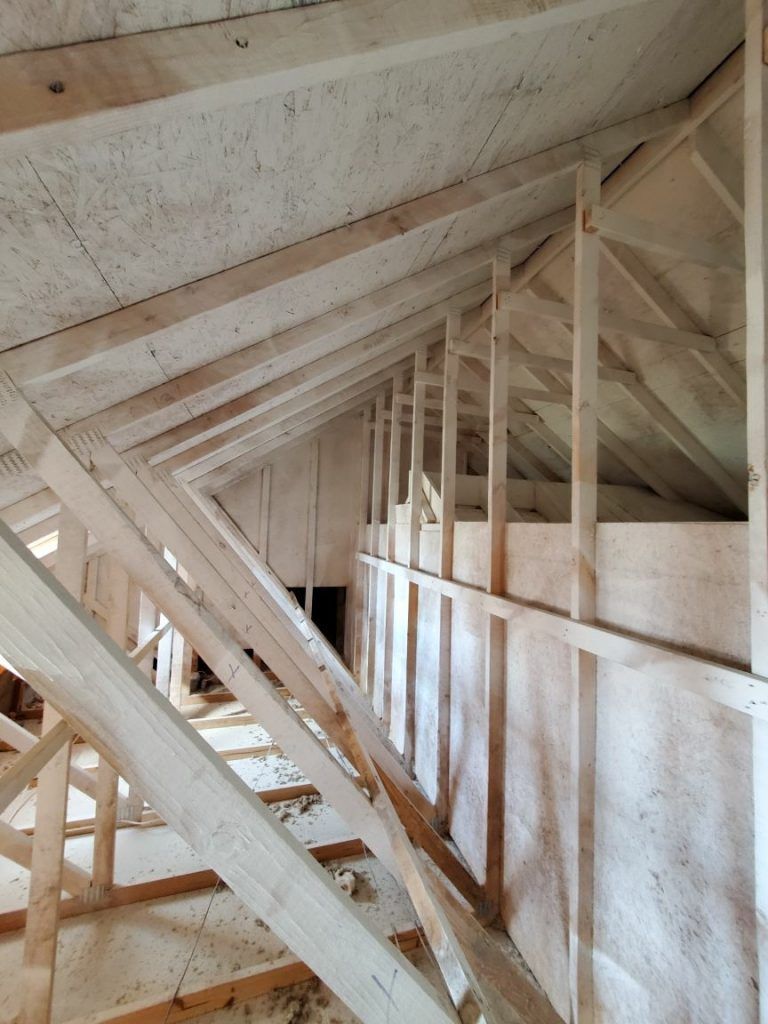 The inside of a house under construction with wooden beams being repaired from fire damage.