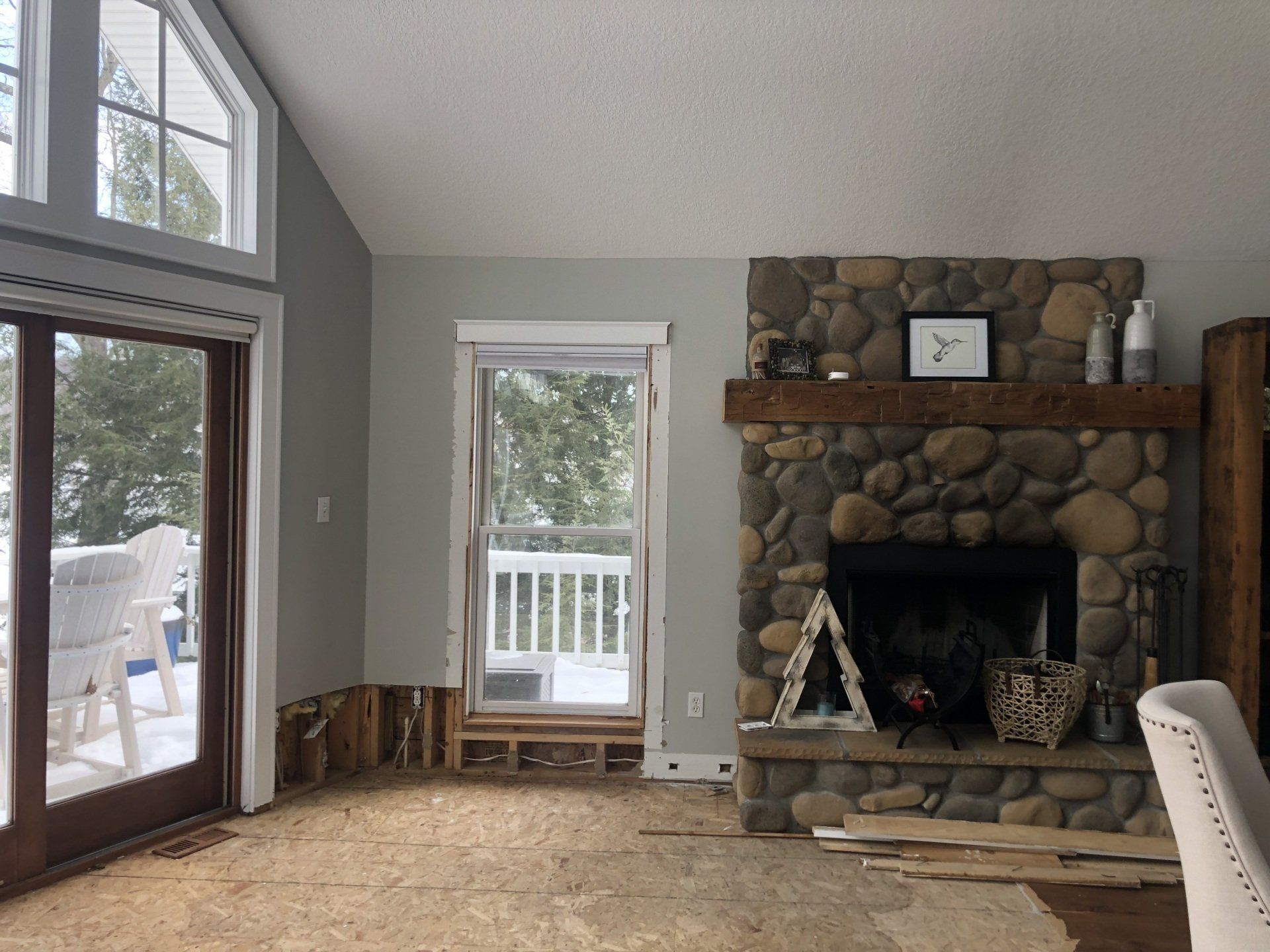 A living room with a stone fireplace and sliding glass doors.