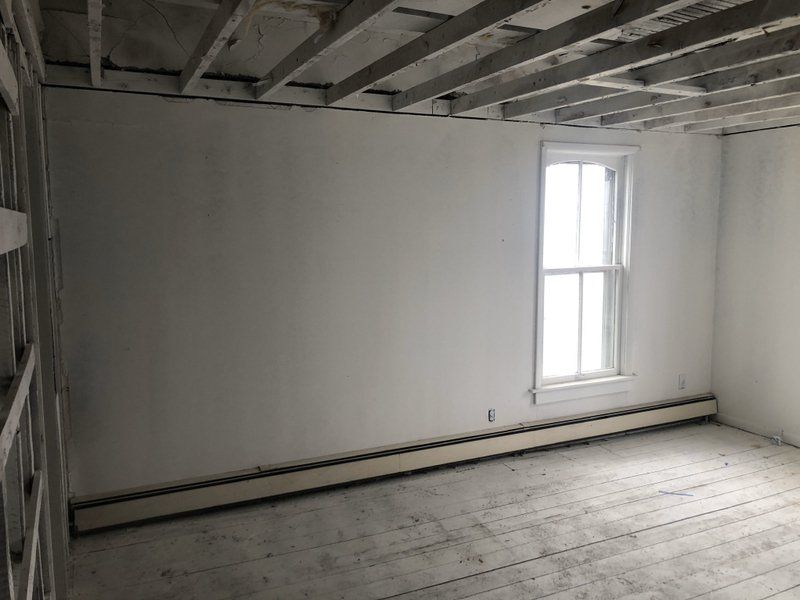 An empty room with a window and a wooden floor.