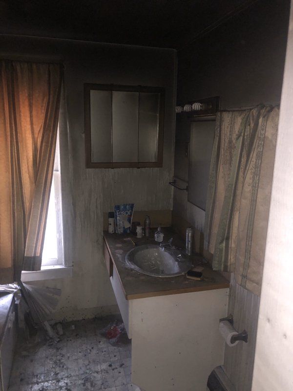 A bathroom with a sink , mirror and window.