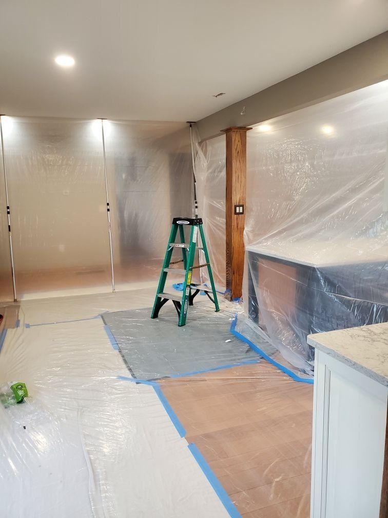 A ladder is sitting in a room covered in plastic.