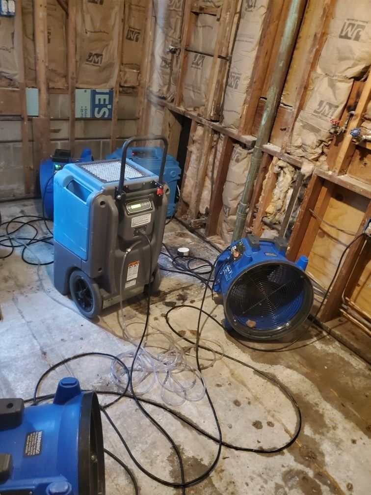A room with an industrial machine and fan that has been water damaged. 
