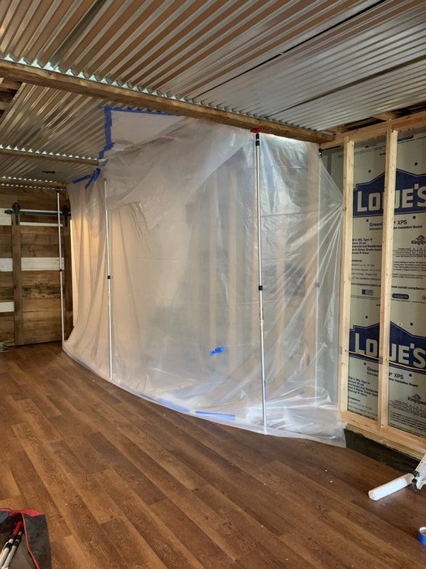 A room being repaired with plastic covering over the wall frame.