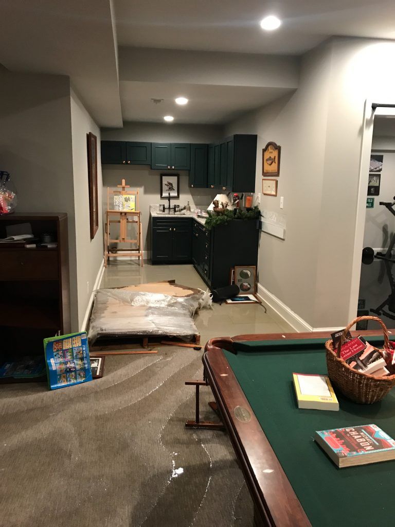 A basement with a pool table and a basket of books