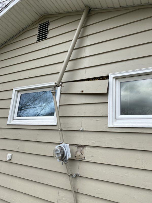 A house with a broken siding and two small windows.