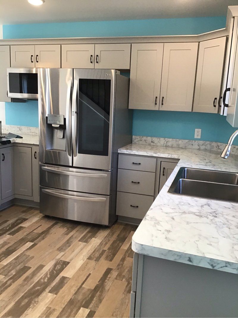 A kitchen with stainless steel appliances, white cabinets and a blue wall.
