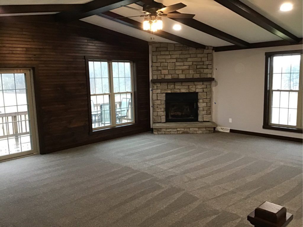 An empty living room with a fireplace and a ceiling fan.