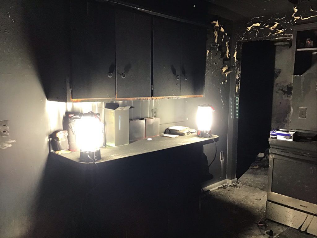 A kitchen with black cabinets and a light on the counter